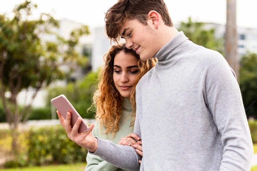Teen couple looking at phone, modern aesthetic