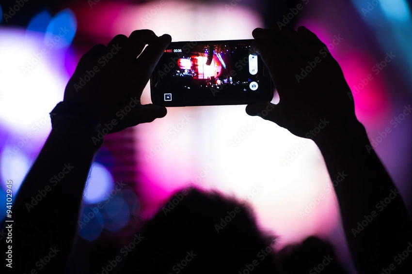 Teen boy at a concert, phone in hand, blurry background