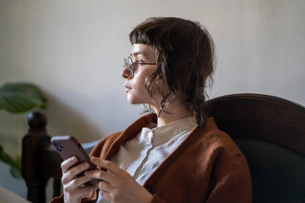 Thoughtful teen girl looking at phone, privacy concerns