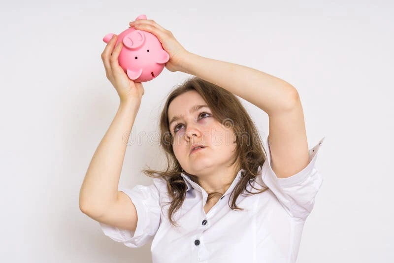 woman looking thoughtfully at empty piggy bank