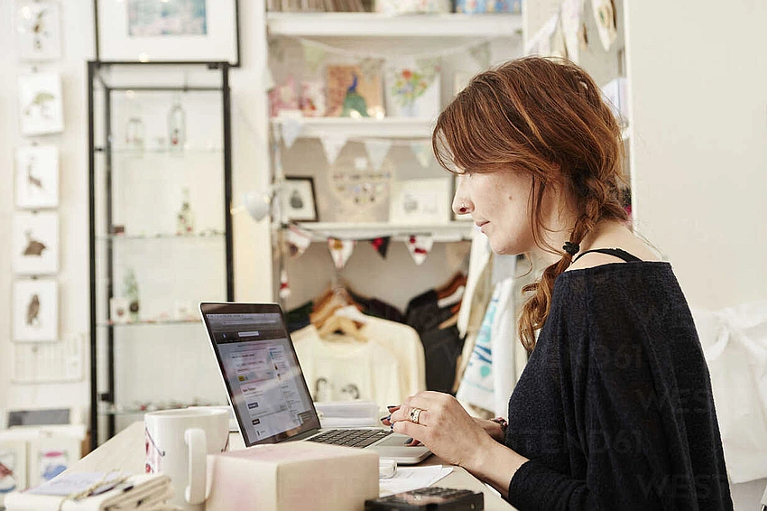 Online shop setup, person with laptop and handmade items