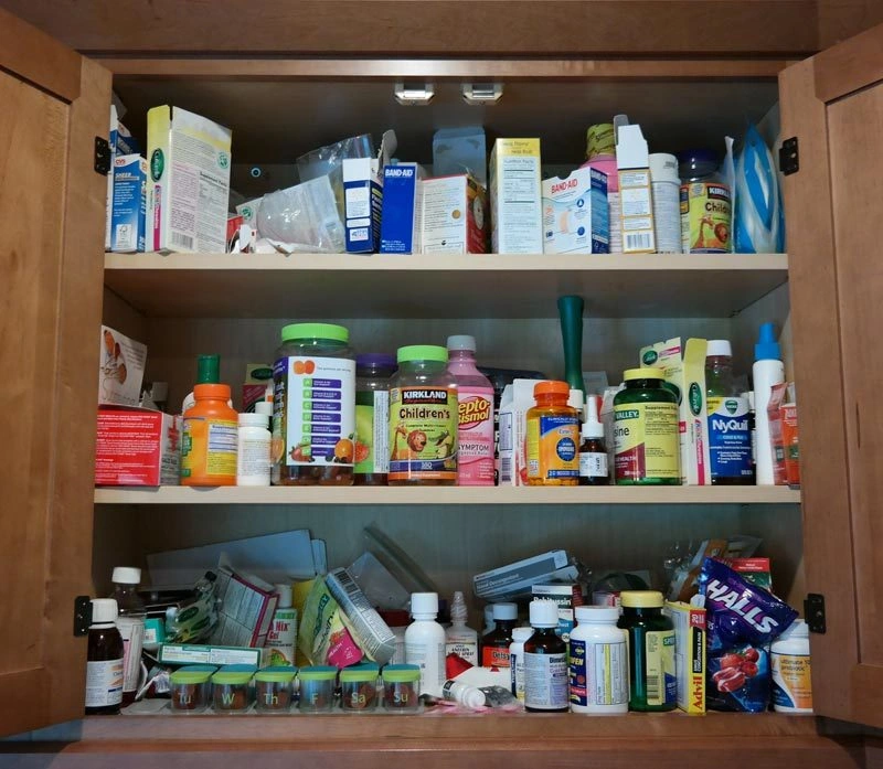 cluttered medicine cabinet, person confused by supplement bottles