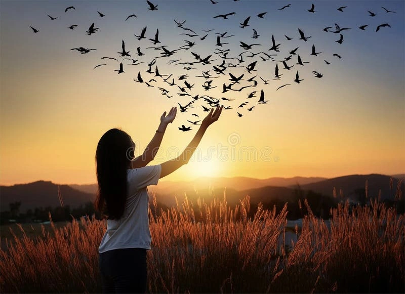 Woman meditating in nature, person letting go of a paper bird, hands releasing grip