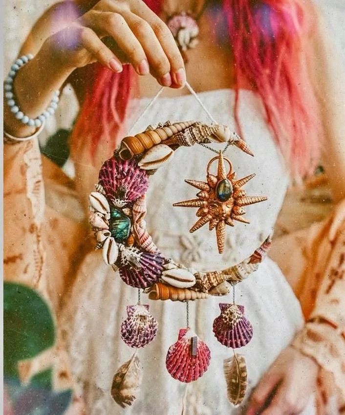 Woman with a thoughtful, knowing smile, holding a delicate, symbolic object like a shell or a dream catcher