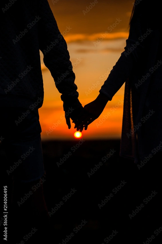 Couple walking hand in hand at sunset, silhouettes, romantic, cinematic.