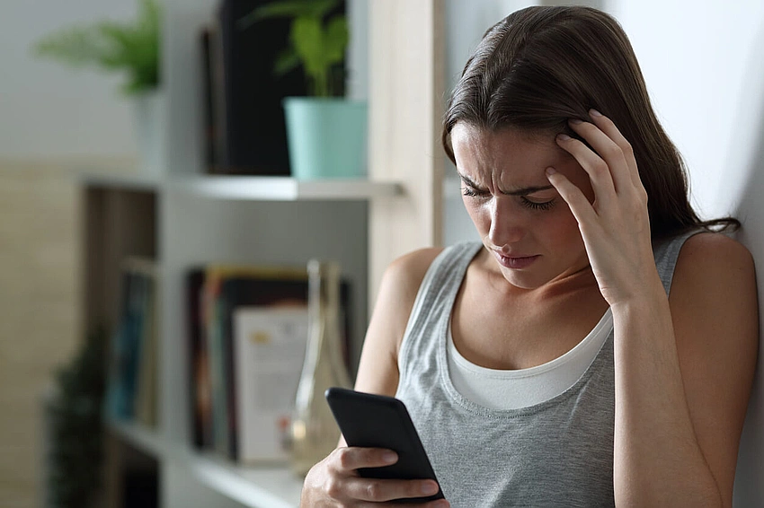 Teenager looking at phone with a thoughtful expression